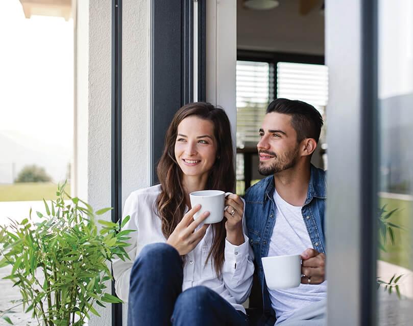 Woman and man sitting in door frame drinking coffee