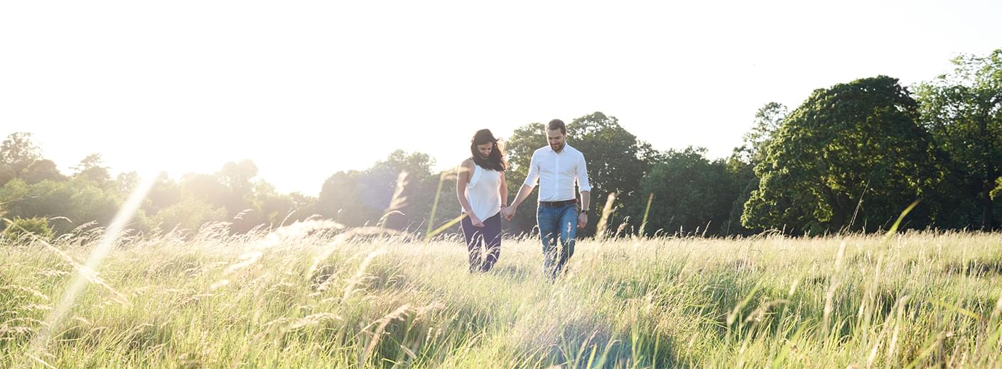 A couple holding hands while walking through a grassy field