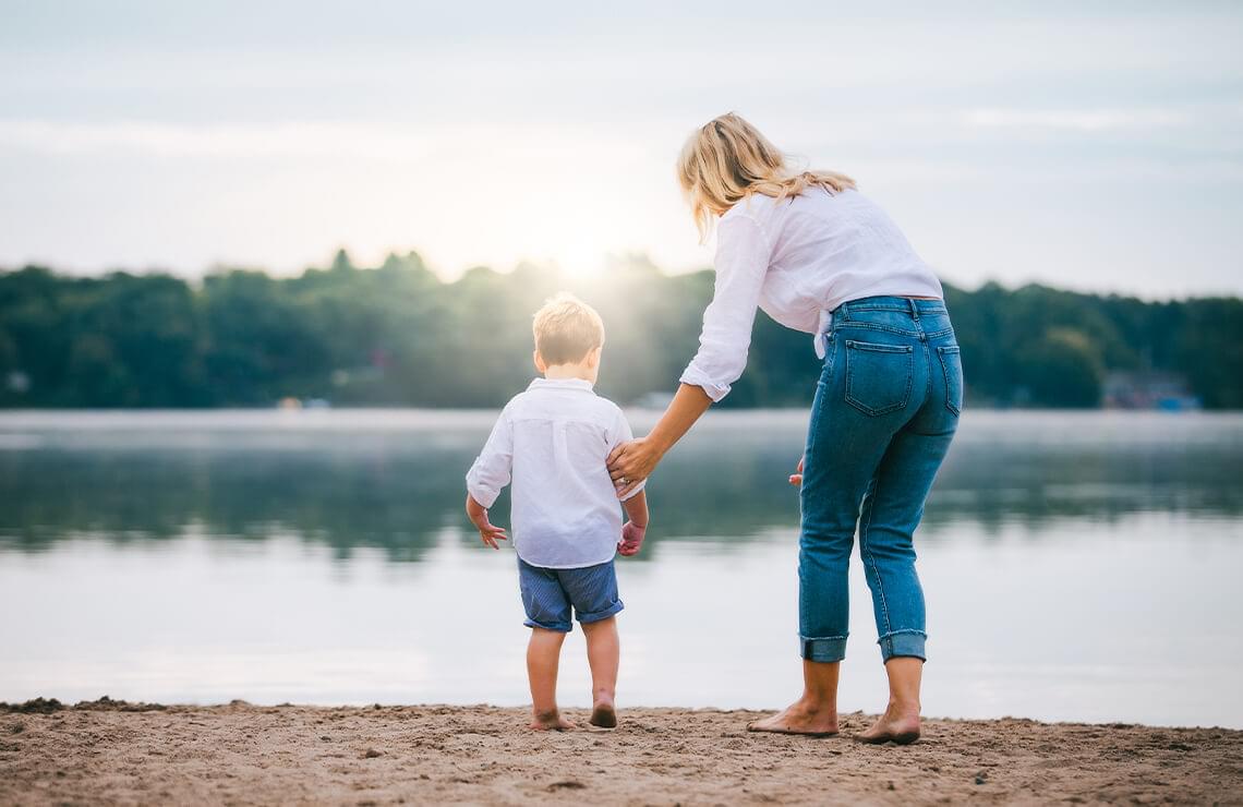 Woman holding sons arm standing at each of beach