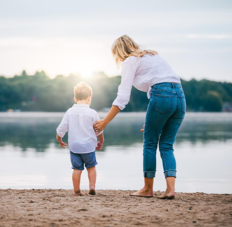 Woman holding sons arm standing at each of beach