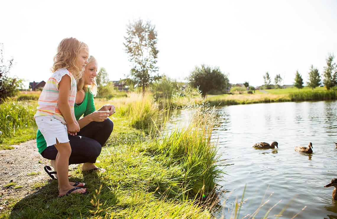 Woman and daughter standing at the edge of a pond