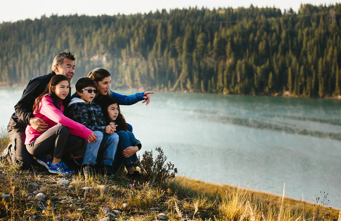 Family sitting along hill with wetland in background