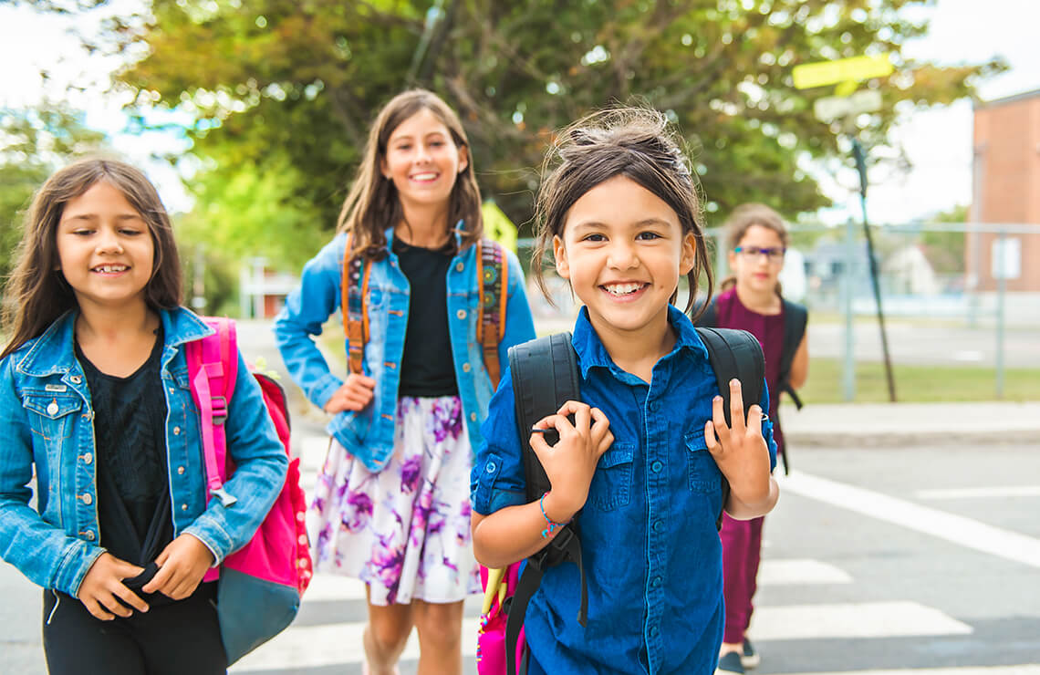 Group of smiling kids with backpacks walking to school