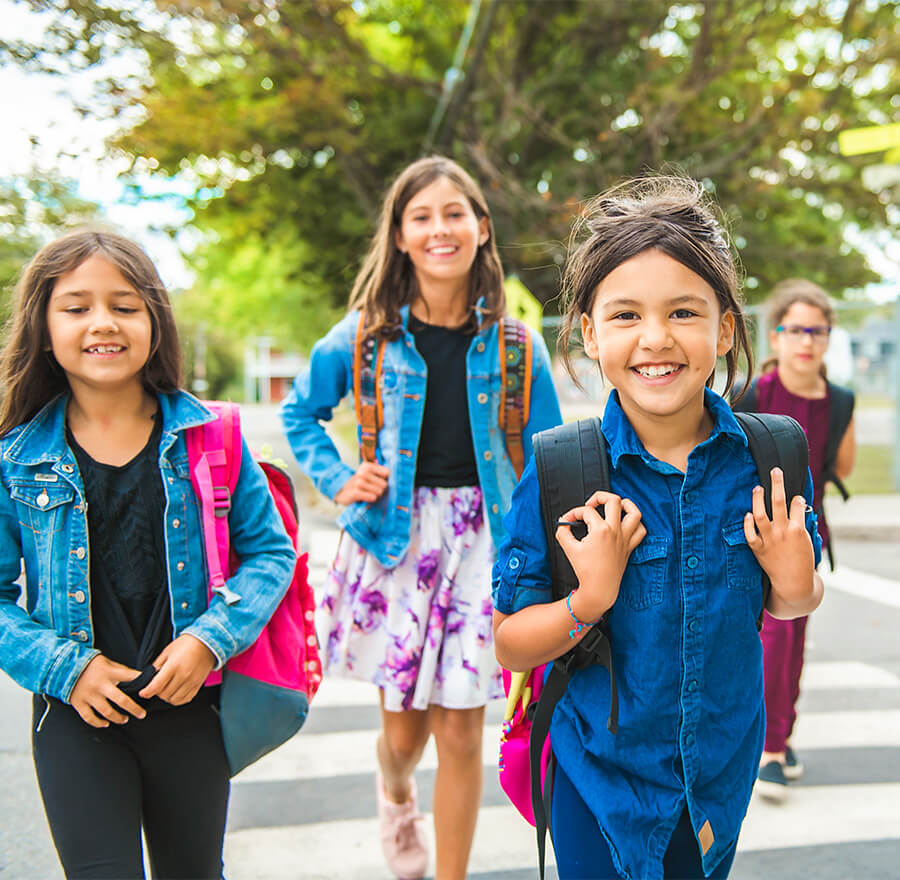 Group of smiling kids with backpacks walking to school