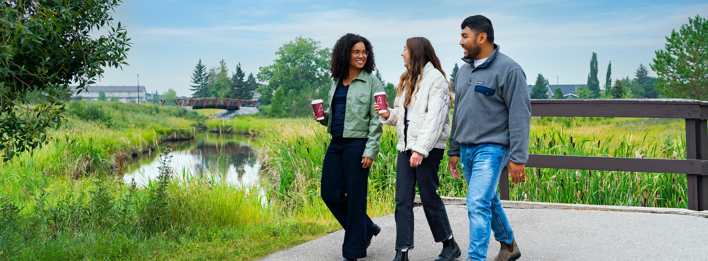 Two women and a man walking through a wetland area