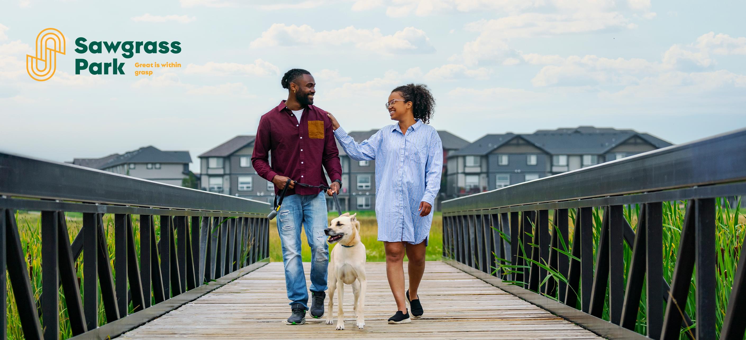 A couple walking their dog across a bridge